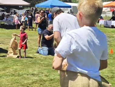Kids having sack races in the Placerville Plaza with vendors in background